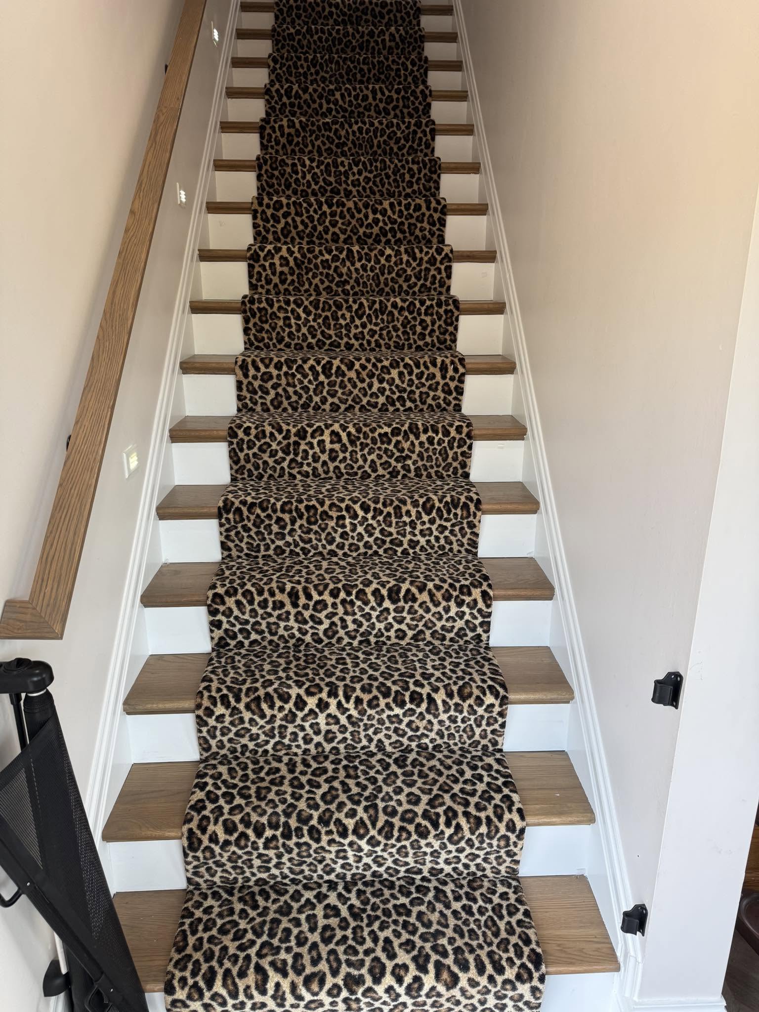 A leopard-print carpet runner on white-and-wood stairs.