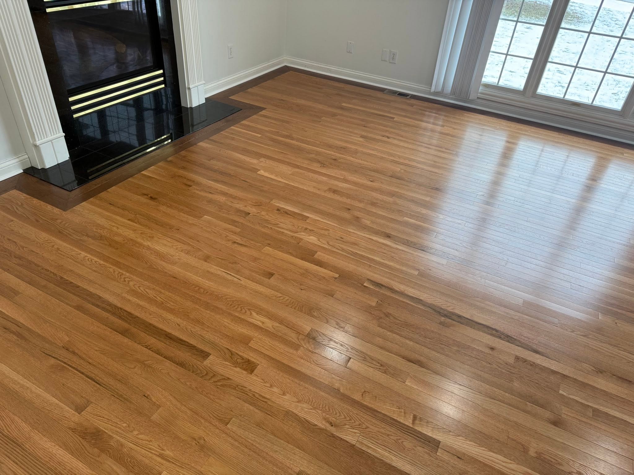 Hardwood flooring with a contrasting border, in a living room with a fireplace.
