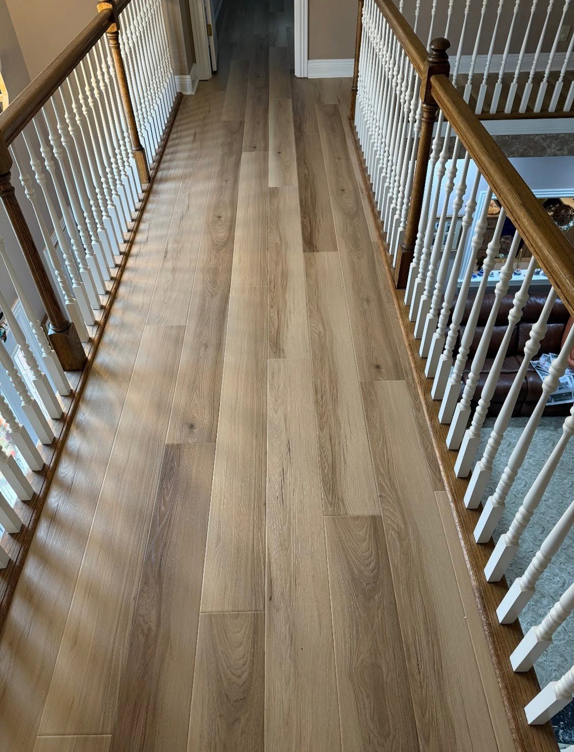 Tarkett Taylored Hickory waterproof flooring along an upstairs balcony with white railings.