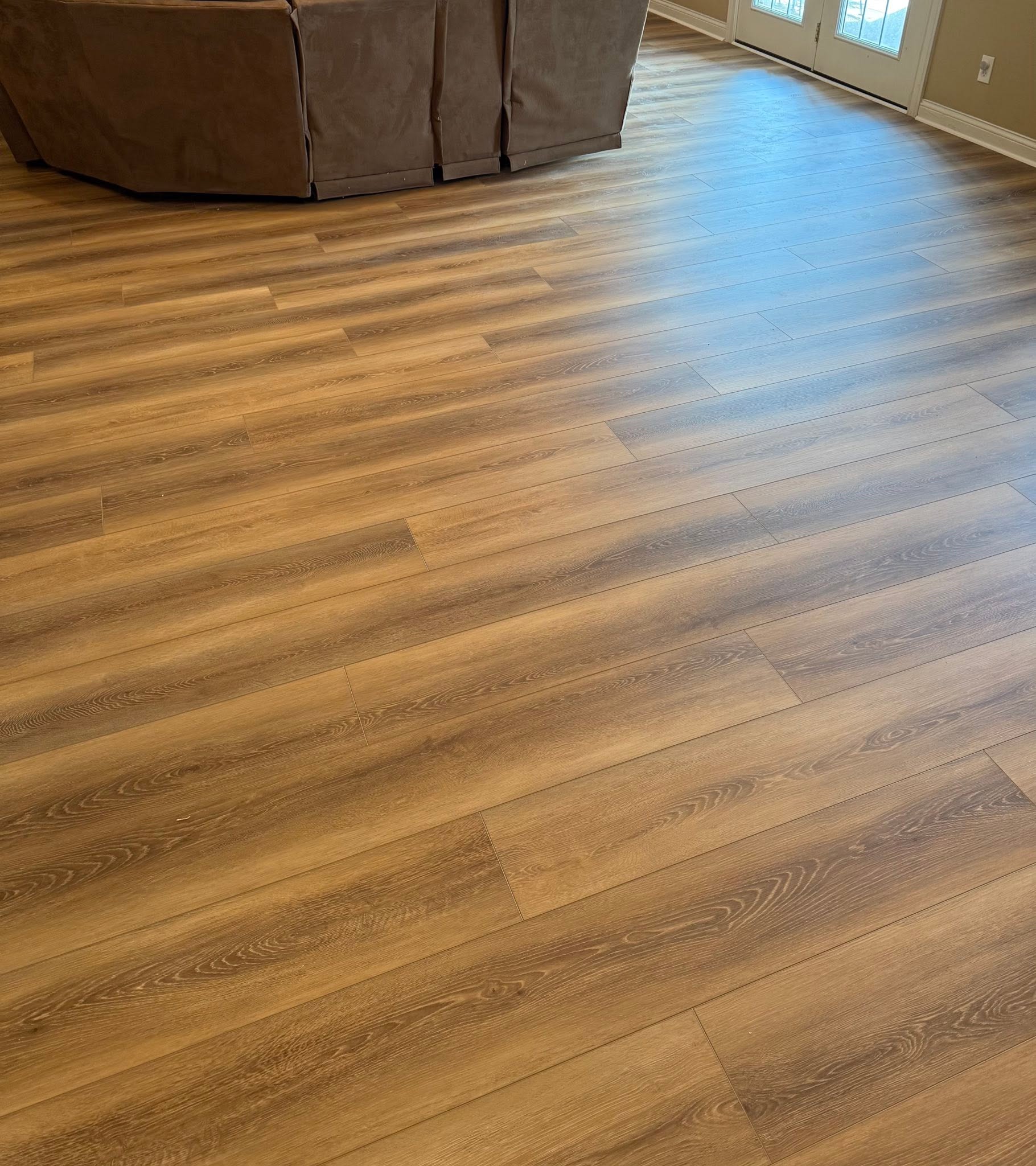 Audacity Symphony flooring in the color Tyler, in a living room with a sectional sofa.