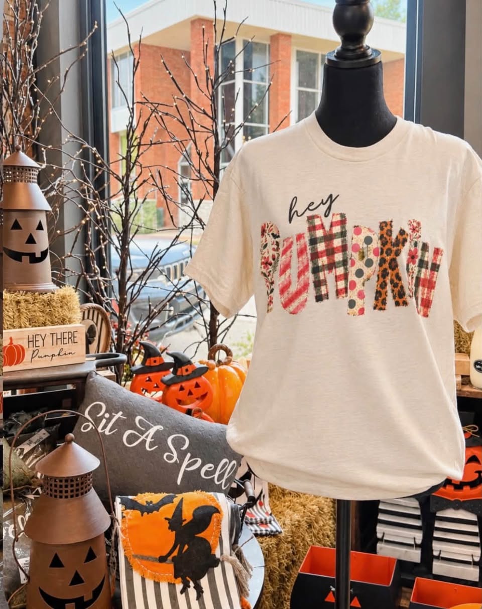 A Hey Pumpkin graphic tee on display in the Gift Shop window, surrounded by fall decor.
