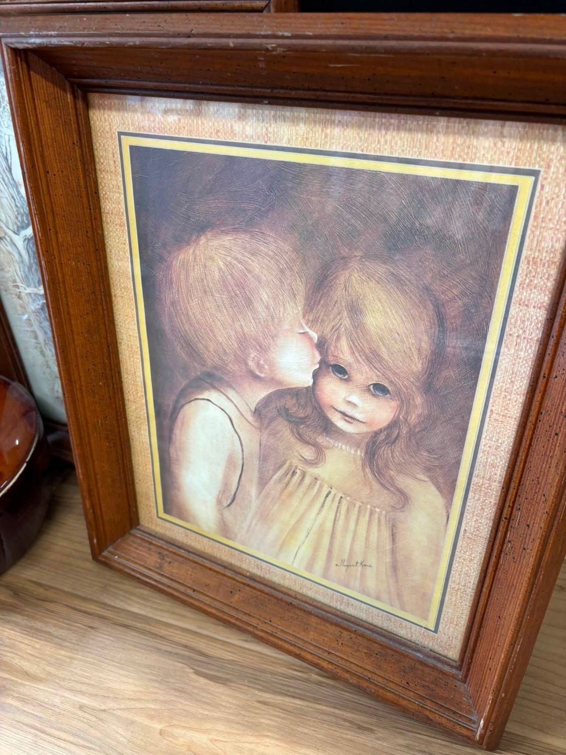 A framed vintage art print in a wood frame, signed Margaret Keane.