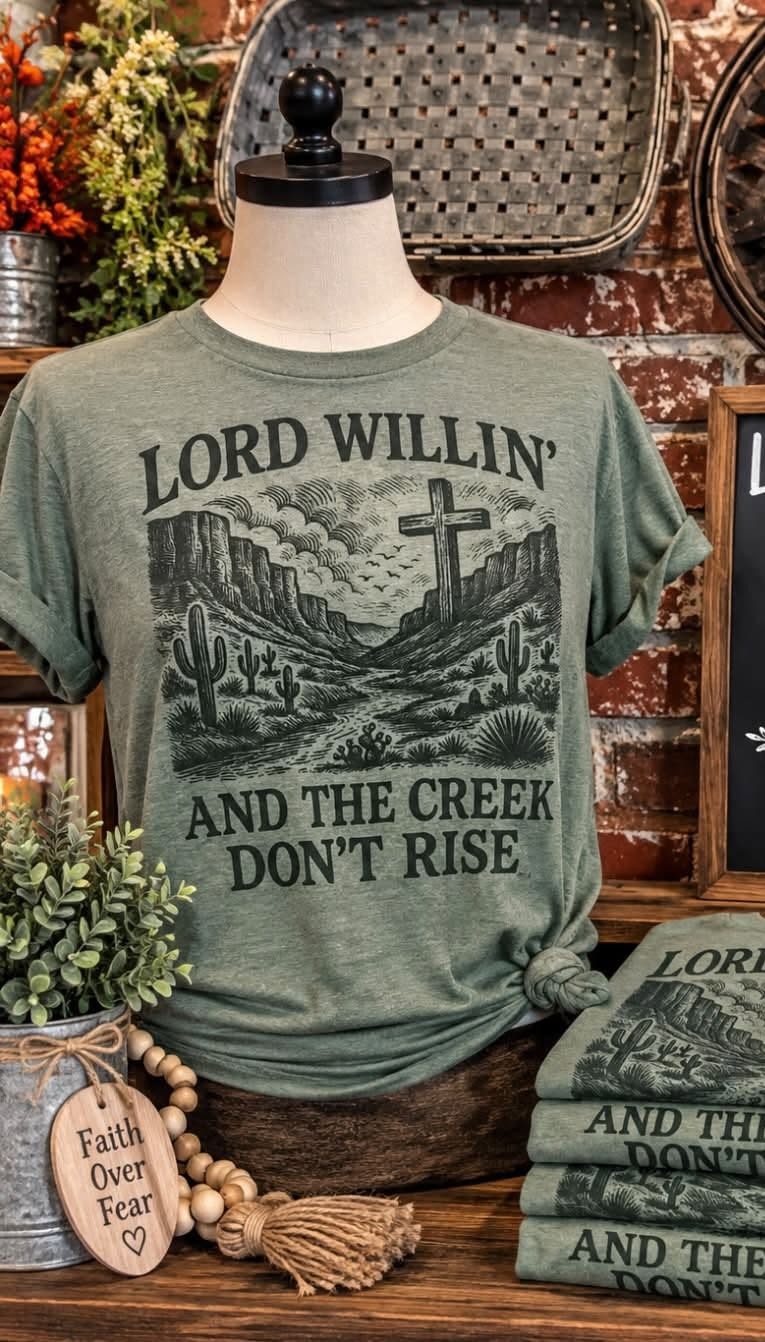 A Lord Willin' and the Creek Don't Rise graphic t-shirt on display.