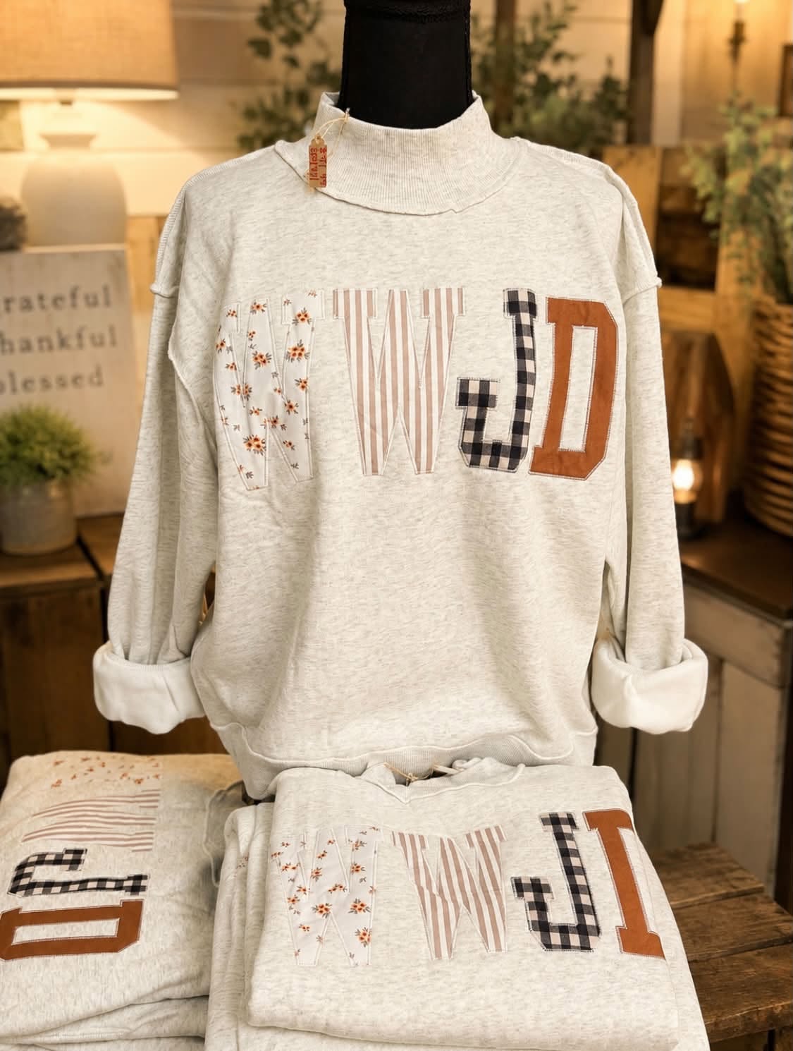 A WTWJD patchwork mock neck sweatshirt on display.