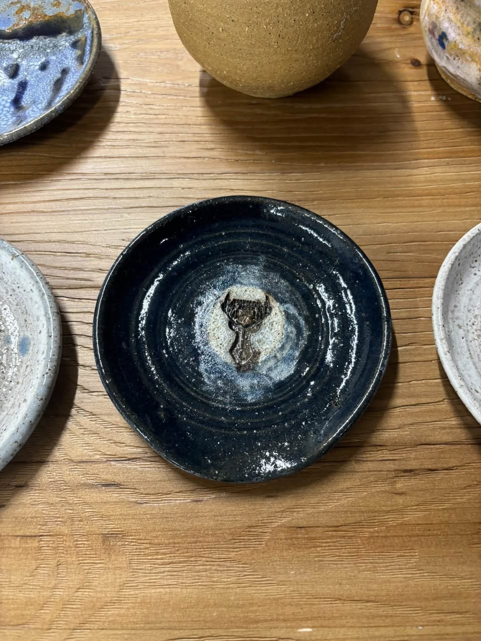 A handmade pottery dish with a dark speckled glaze.