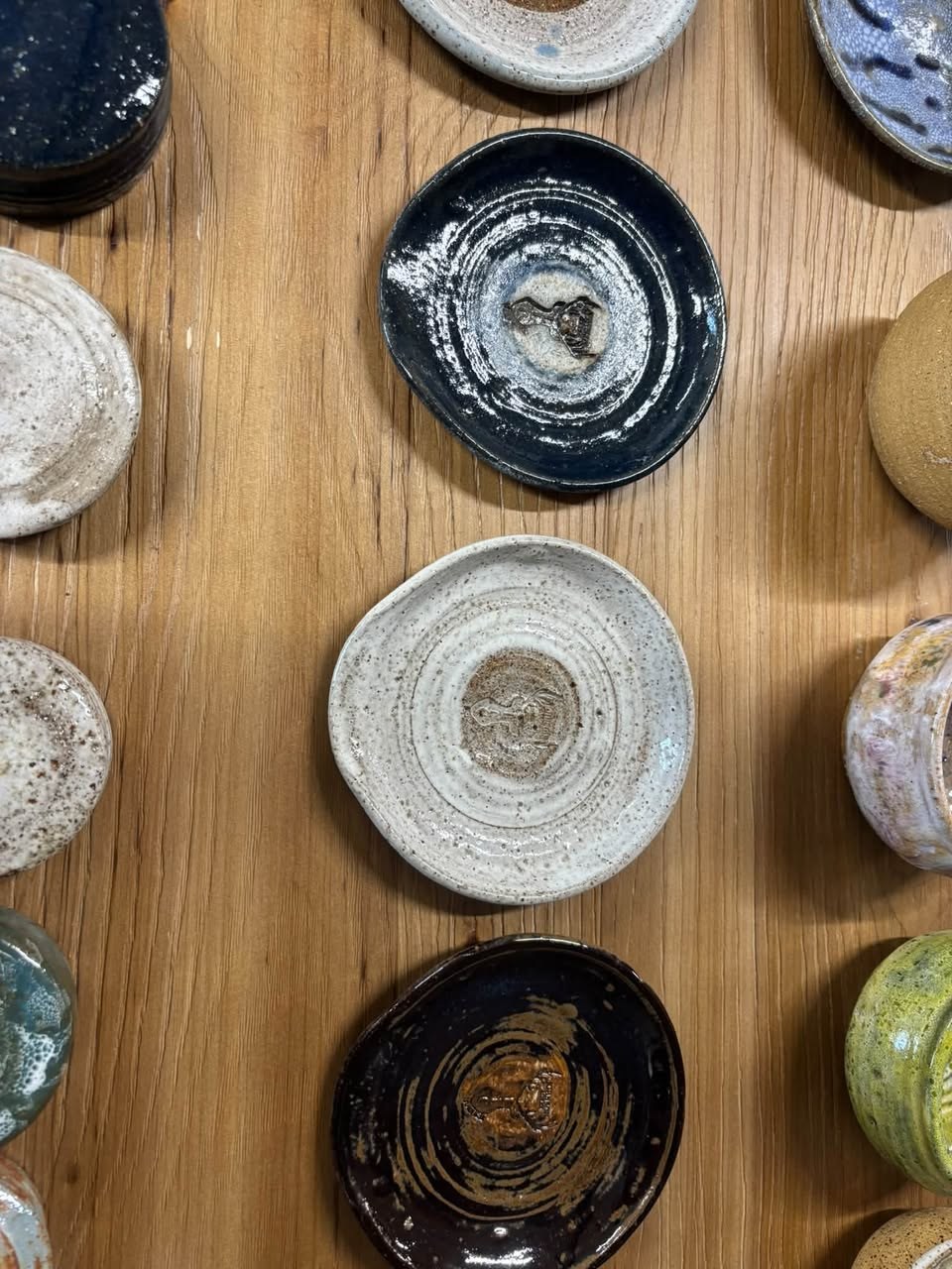 Overhead view of handmade glazed pottery dishes on a wooden table.